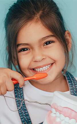 Smiling girl brushing her teeth after pediatric dental services in Riverton